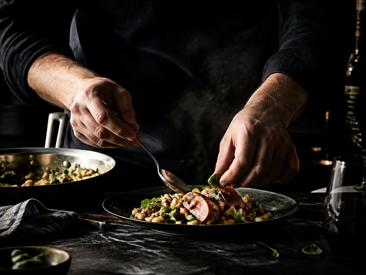 Hands plating a rustic weeknight dinner in moody light